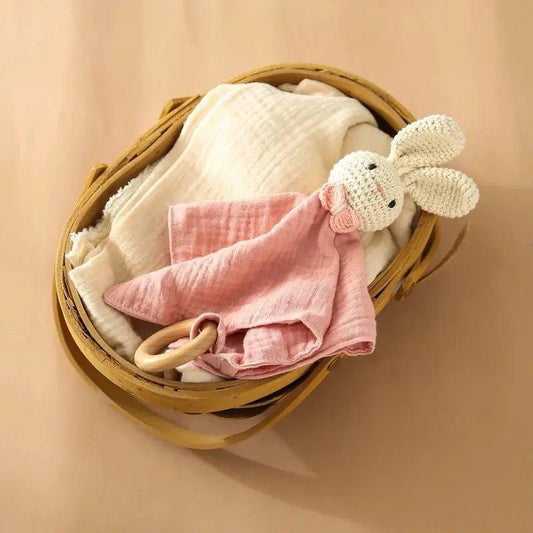 Doudou bébé lapin en crochet et tissu rose dans un panier en osier sur fond beige
