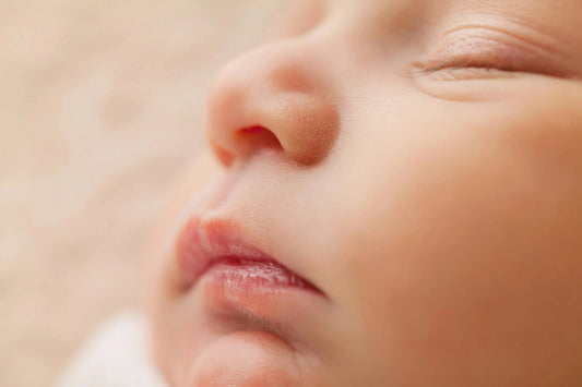 Gros plan visage bébé endormi, peau douce, lèvres et nez, lumière naturelle