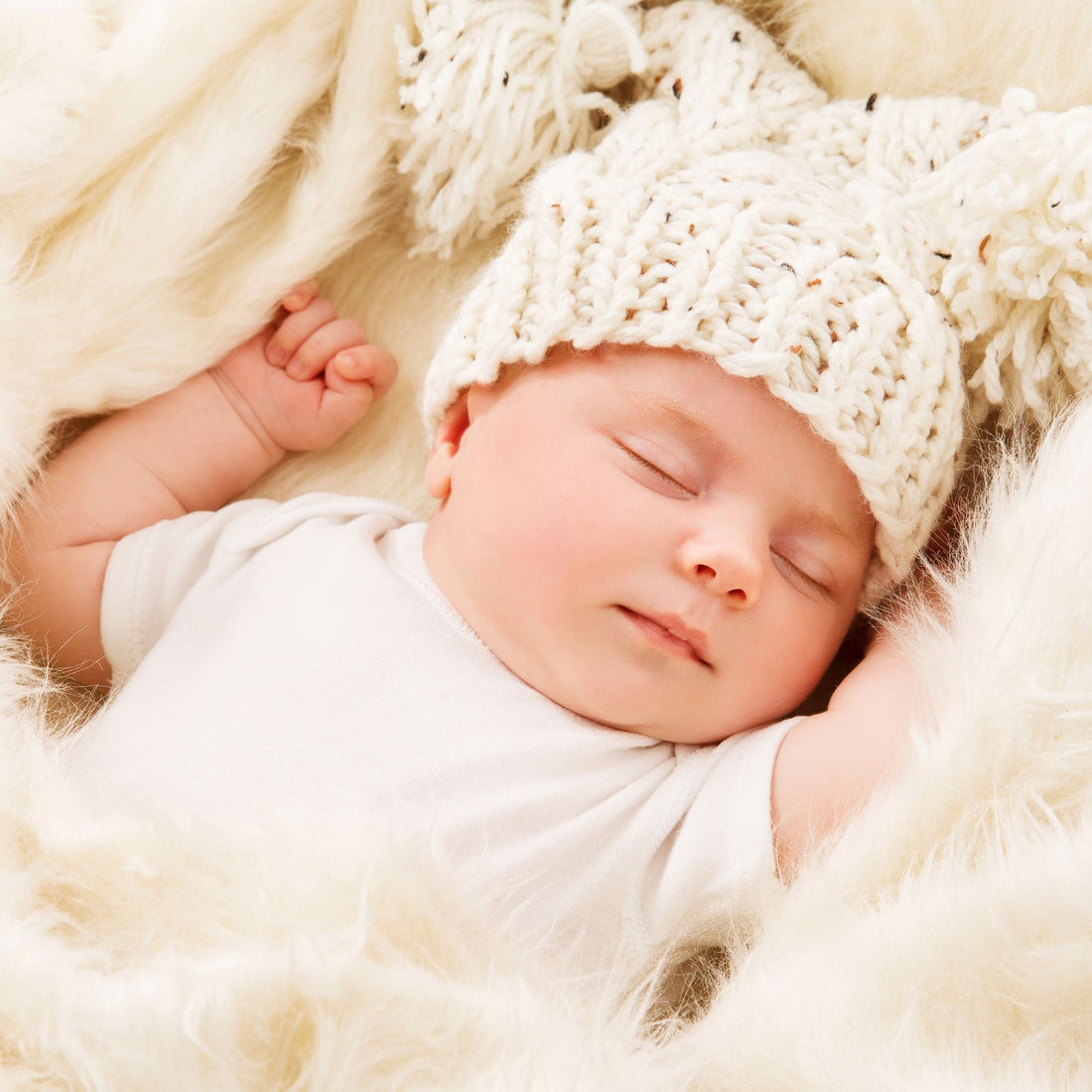 Bébé dormant paisiblement avec bonnet tricoté blanc sur couverture en fausse fourrure