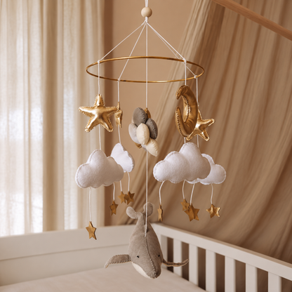 Étoile dorée suspendue du mobile bébé artisanal Baleine & Ballons au-dessus d’un nuage blanc