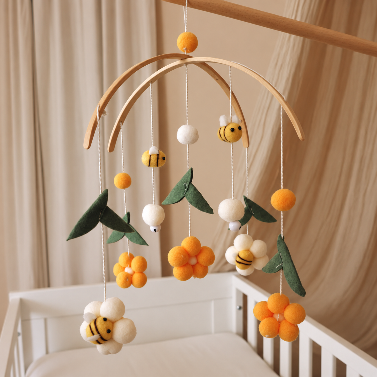 Détail d’un pompon blanc et de feuilles vertes sur le mobile bébé Abeilles jaunes