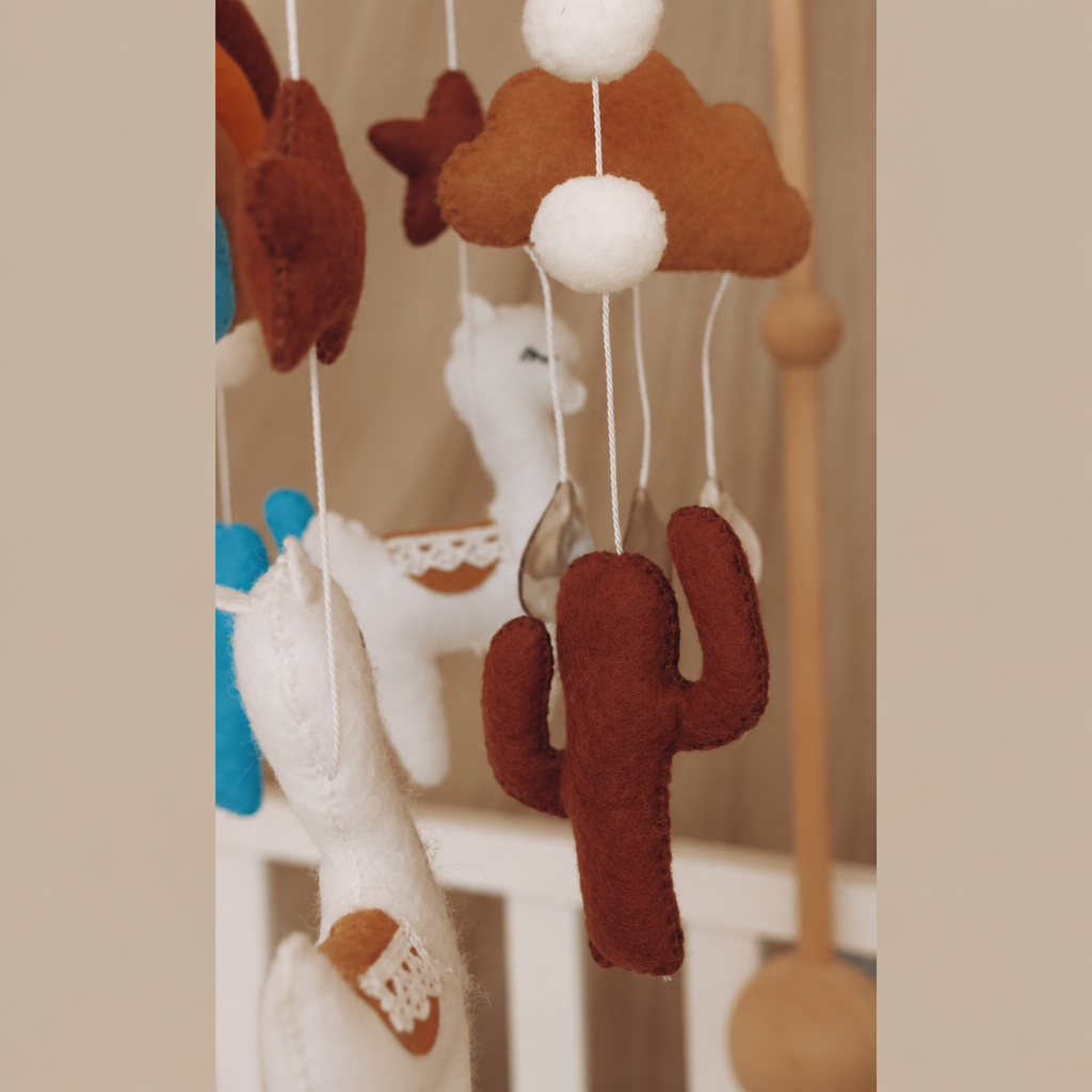 Gros plan sur les éléments en feutre du mobile bébé artisanal Lama