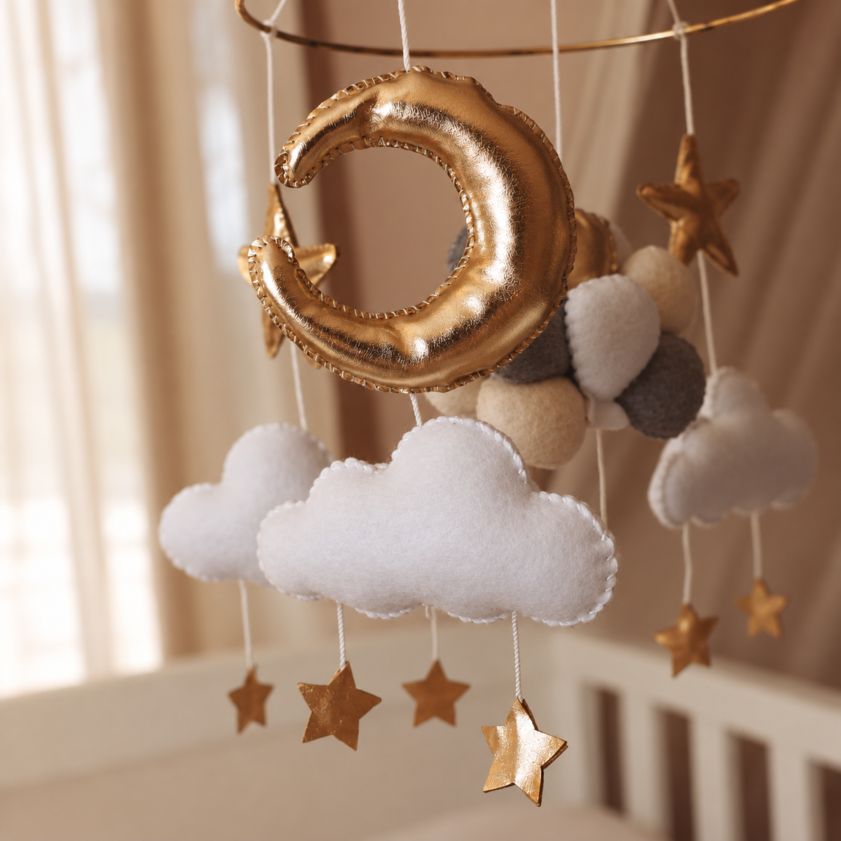 Détail du bouquet de petits ballons en feutre blanc, beige, gris et doré du mobile bébé