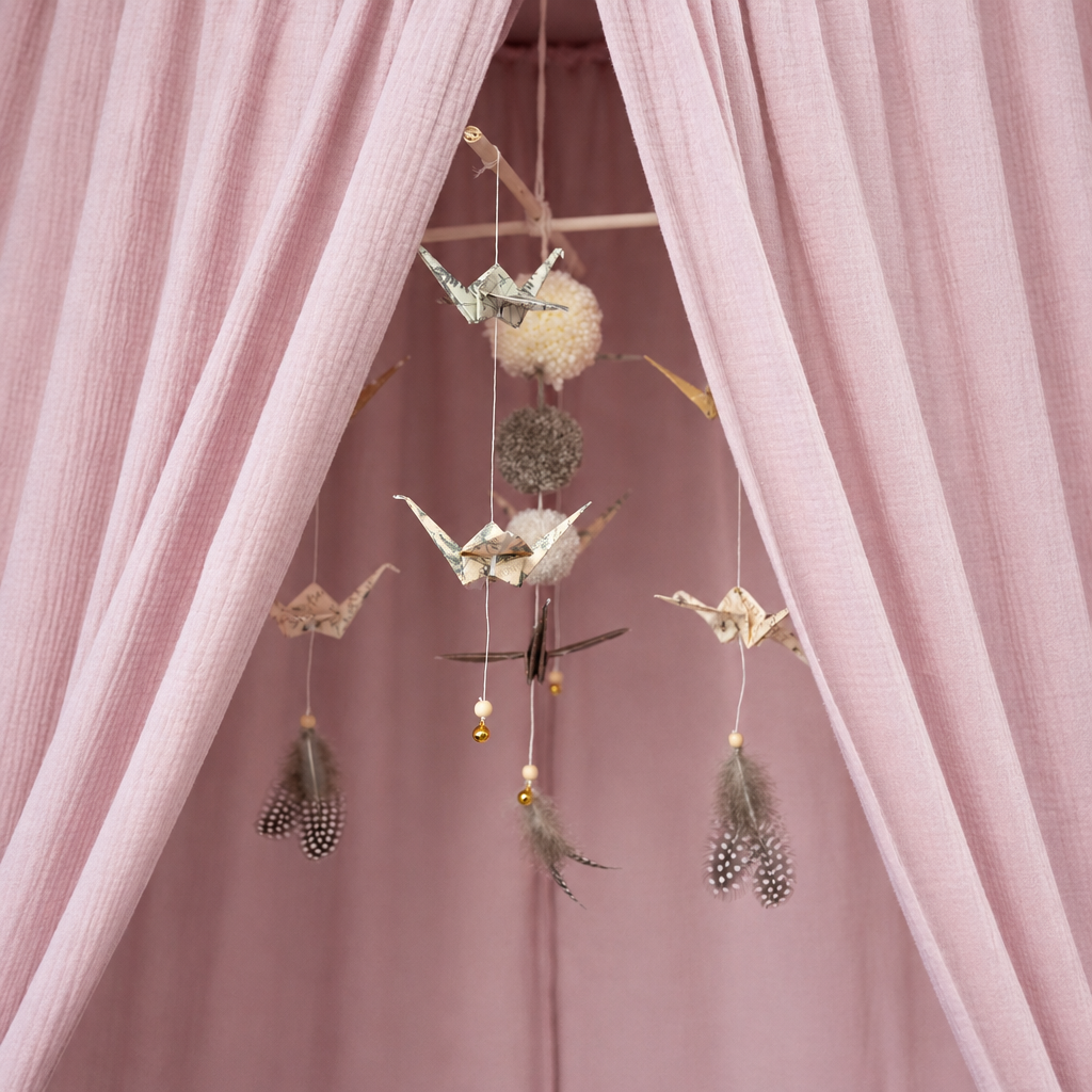 Détail décoratif avec mobile dans une chambre de bébé rose tendre