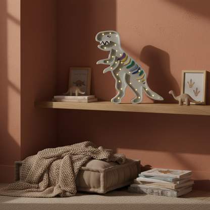 Veilleuse dinosaure T-Rex Little Lights allumée sur une étagère dans une chambre d’enfant décorée aux tons terre cuite et beige