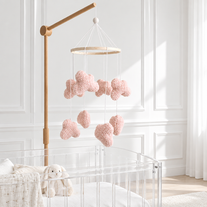 Mobile Nuages bouclés roses avec support en bois dans une chambre contemporaine blanche