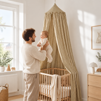Papa avec bébé sous le ciel de lit en coton rayures olive dans une chambre lumineuse