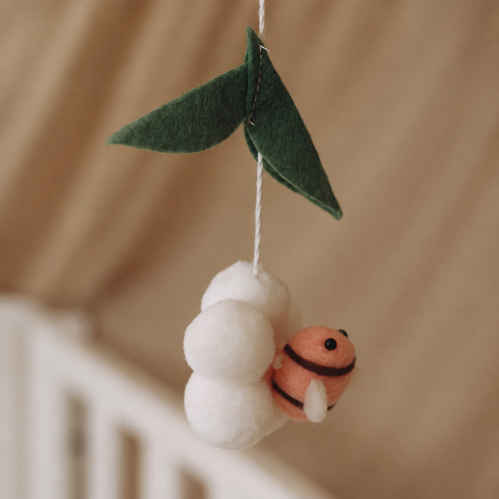 Détail d’une abeille rose suspendue sur le mobile bébé artisanal