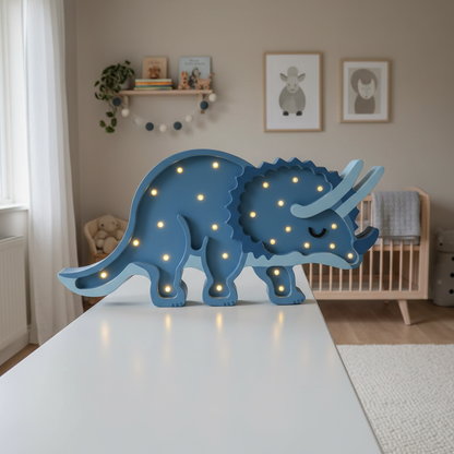 Veilleuse bébé Tricératops bleue allumée dans une chambre scandinave