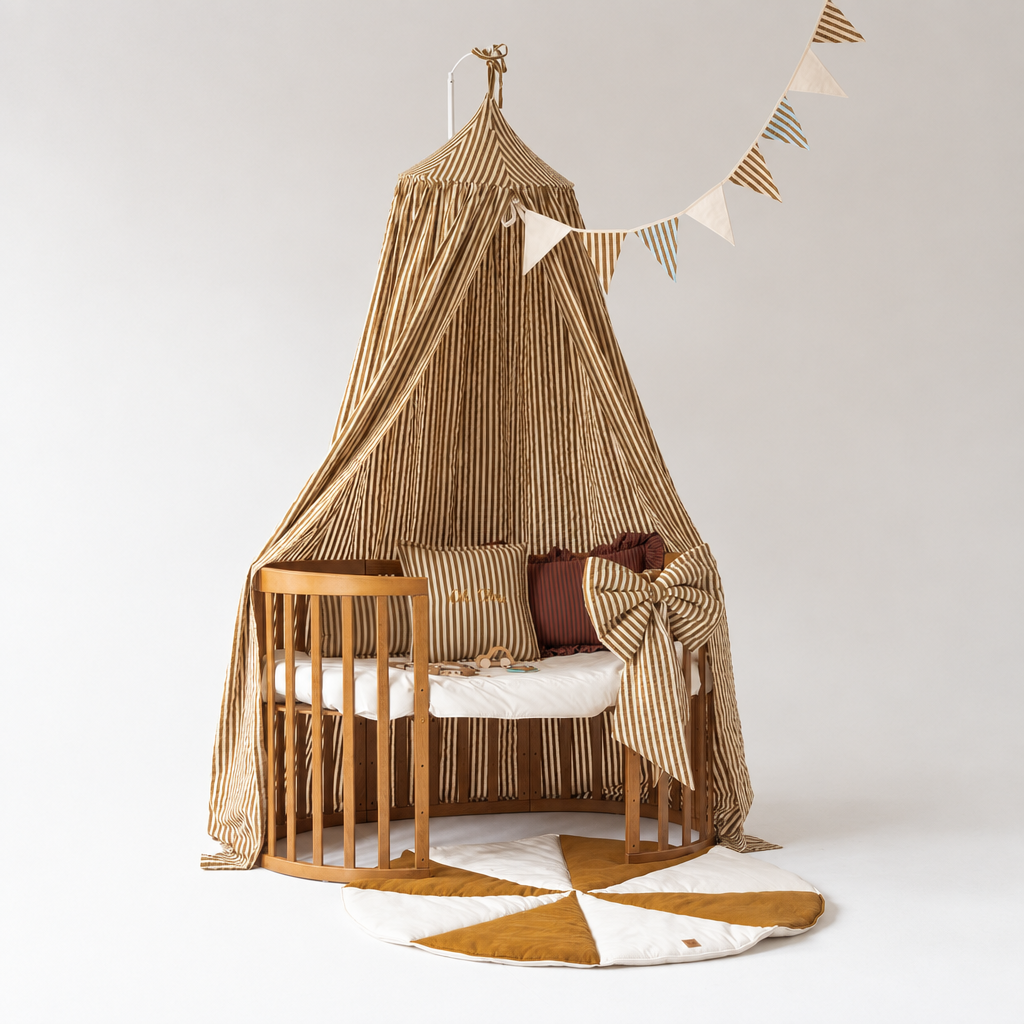 Ciel de lit bébé rayures olive au-dessus d’un berceau ovale en bois