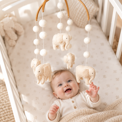Bébé observant le mobile artisanal Éléphants au-dessus du berceau